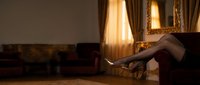 Woman relaxing on luxury sofa in elegant living room with warm golden lighting and classic interior design for lifestyle and comfort concepts.