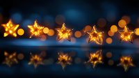 Glowing golden star lights with bokeh effect reflected on dark blue surface, creating magical festive atmosphere for holiday decorations and celebrations.