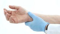 Doctor in blue medical glove examining patient wrist, checking pulse or diagnosing joint pain, isolated on white background.