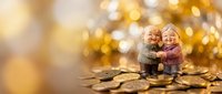 Elderly couple figurines embracing on pile of golden coins with warm bokeh lights background symbolizing retirement savings and financial security.