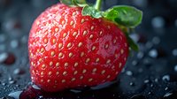 Fresh ripe strawberry with water drops on dark background, macro shot showing detailed texture and seeds, vibrant red color and green leaves.
