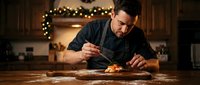 Professional chef plating gourmet dish in warm kitchen with festive lights, culinary artistry and fine dining preparation for restaurant service.