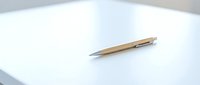 Elegant wooden ballpoint pen lying on clean white paper surface for business writing and professional correspondence in modern office setting.