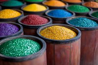 Vibrant colored powder pigments in wooden bowls, featuring metallic gold, purple, blue, green, and yellow dyes arranged in traditional containers for art and decoration.