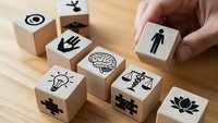 Wooden cubes with business icons including brain, lightbulb, scales, puzzle pieces and human figures for corporate strategy concepts.