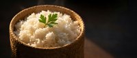 Steamed white rice in rustic wooden bowl garnished with fresh parsley on dark background. Healthy grain side dish for Asian cuisine and comfort food recipes.