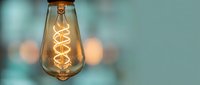 Vintage Edison bulb with glowing spiral filament against soft bokeh background. Retro lighting design element for modern interior decoration and ambiance.