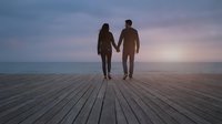 Couple holding hands on wooden pier at sunset, romantic relationship and togetherness concept for travel, love, and lifestyle design projects.