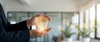 Businessman holding glowing shield icon with digital network connections, representing cybersecurity, data protection, and secure business solutions for corporate safety.