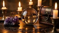 Mystical fortune telling setup with crystal ball, amethyst crystals, vintage treasure chest and burning candles creating atmospheric divination scene.