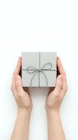Hands holding wrapped gift box with gray ribbon on white background for holiday celebrations and special occasions.