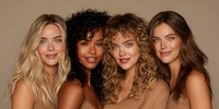 Diverse group of women with different hair textures - blonde, curly, and brunette - smiling against neutral beige background, perfect for beauty and fashion campaigns.