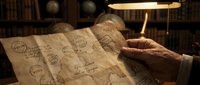Aged hands examining vintage map with stamps and markings under warm lamp light in study room with books and globe in background.