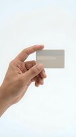 Hand holding blank transparent credit card mockup on white background for financial services and banking design projects.