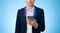 Young Caucasian male professional in dark blazer holding smartphone with glowing purple holographic interface display against blue background for technology and business concepts.
