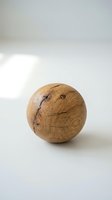 Handcrafted wooden sphere with natural grain patterns and cracks on white background for home decor and artisan craft projects.