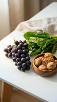 Fresh organic produce arrangement with purple grapes, leafy greens and mixed nuts in wooden bowl on white kitchen counter for healthy eating lifestyle.