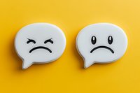 White speech bubble emoticons showing sad and angry faces on vibrant yellow background, representing negative feedback, disappointment and customer dissatisfaction.