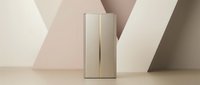 Modern beige refrigerator with sleek handles against geometric pastel background for contemporary kitchen design and home appliance advertising.