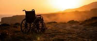 Empty wheelchair silhouetted against golden sunset in desert landscape, symbolizing hope, resilience, and overcoming challenges during rehabilitation or recovery journey.