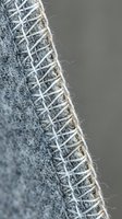 Gray burlap fabric edge with visible weave pattern and frayed threads. Natural jute textile material for rustic crafts and home decor projects.