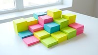 Colorful stacked wooden blocks arranged in geometric pattern on white surface, featuring bright yellow, pink, cyan, and lime green cubes for creative play and learning activities.
