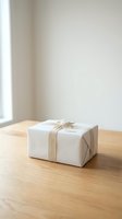 Minimalist white gift box tied with twine ribbon on a wooden table, soft natural light, clean neutral background for holiday or celebration concepts.