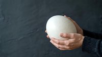 Hands holding white sphere against dark textured background, suitable for business concepts, innovation, ideas, and design projects.
