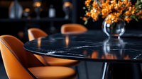 Modern round black marble dining table with orange leather chairs and floral arrangement in dark moody restaurant interior setting with dramatic lighting.