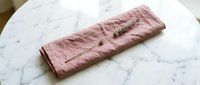 Folded dusty rose linen napkin with natural texture on white marble surface, ready for table setting and event styling.