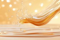 Golden liquid splash with flowing waves and droplets creating dynamic motion against warm bokeh background for beverage and cosmetic advertising.