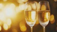 Two champagne flutes filled with sparkling wine against warm golden bokeh background, perfect for celebration, toast, and festive event marketing materials.