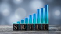 Professional development concept with wooden letter blocks spelling SKILL and ascending blue bar chart representing growth and improvement in abilities.