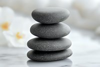 Balanced stack of smooth gray zen stones on light background creates peaceful spa atmosphere for wellness and meditation practices.