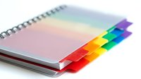 Spiral bound notebook with blank pages and colorful rainbow divider tabs for organization, planning, and note-taking in office and school settings.