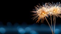 Glowing golden fireworks bursting against dark night sky with blue bokeh lights, creating magical festive atmosphere. Perfect for celebration designs.