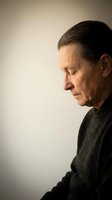 Thoughtful senior man in profile wearing dark sweater against neutral background, contemplating life decisions and reflecting on memories.