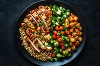 Grilled chicken breast with quinoa, roasted sweet potatoes and fresh broccoli on black plate. Healthy balanced meal with protein and vegetables.