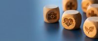 Wooden dice with healthcare and medical symbols on blue surface for wellness concept design and medical industry presentations.