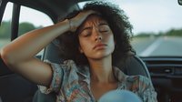 Young mixed-race woman with curly hair experiencing headache or stress while sitting in vintage car interior during road trip journey.
