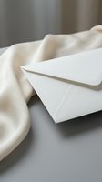 White envelope on soft beige fabric with elegant lighting for correspondence, wedding invitations, business communications and stationery design projects.