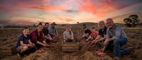 Archaeological team excavating ancient artifacts at sunset dig site with dramatic colorful sky and rural landscape background for educational content.