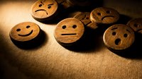 Wooden emotion faces showing different moods from happy to sad arranged on textured surface. Customer service feedback concept for business presentations.
