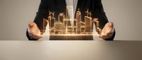 Businessman holding glowing golden cityscape hologram between hands, representing urban development, smart city technology, and future business growth opportunities.