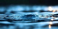 Mesmerizing water ripples creating concentric circles on dark blue surface with soft bokeh light reflections, macro photography showing liquid motion and tranquility.