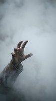 Desperate hand reaching through thick fog and mist seeking help or escape in dramatic atmospheric scene for horror thriller or survival concepts.