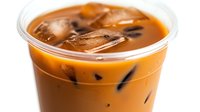 Refreshing bubble milk tea with brown sugar syrup and ice cubes in plastic cup, close up view of trendy Asian beverage against white background.