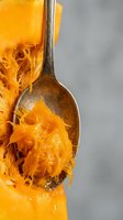 Fresh roasted spaghetti squash strands on wooden spoon, healthy low-carb pasta alternative for cooking and meal preparation on neutral background.