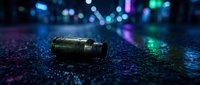Spent bullet casing lies on wet asphalt with neon city lights blurred in background, creating moody crime scene or urban noir atmosphere for film, gaming, or thriller projects.
