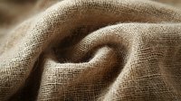 Natural linen fabric with folds and texture in beige color, macro shot showing detailed weave pattern and soft shadows. Suitable for backgrounds.